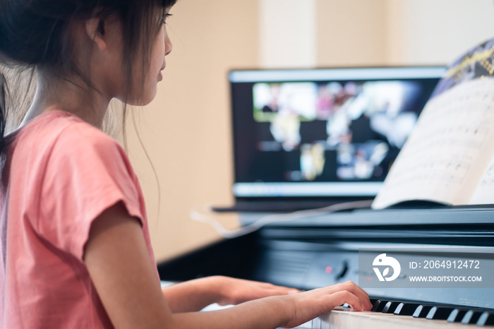 Homeschool Asian young girl learning piano from music online class.