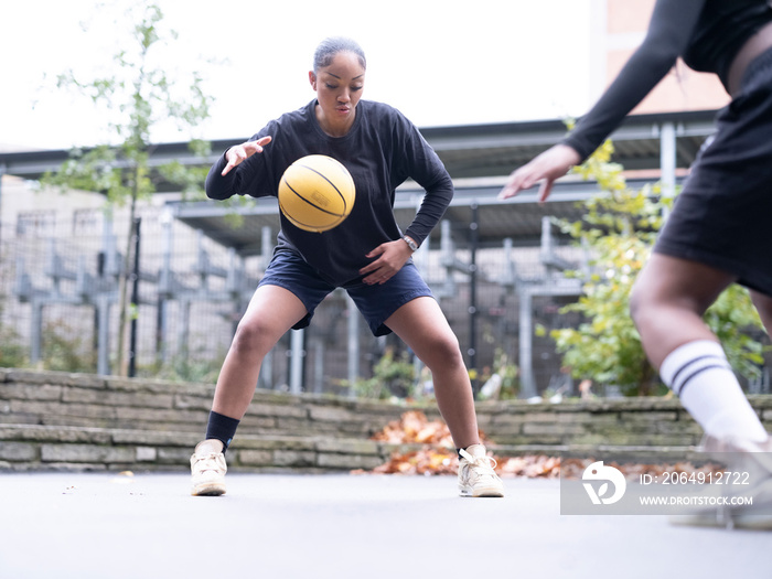 Two female friends playing basketball outdoors