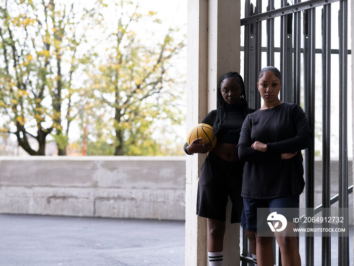 Portrait of female friends standing outdoors with basketball