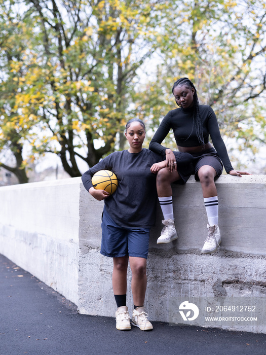 Portrait of female friends outdoors holding basketball ball