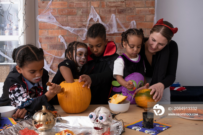 Family in Halloween costumes making Jack�OLantern