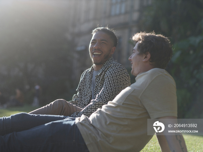 UK, South Yorkshire, Smiling gay couple relaxing on lawn in park