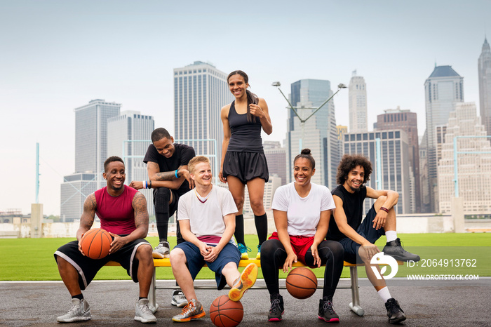 Smiling basketball players sitting on bench outdoors