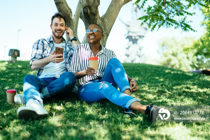 Happy couple relaxing on grass under tree