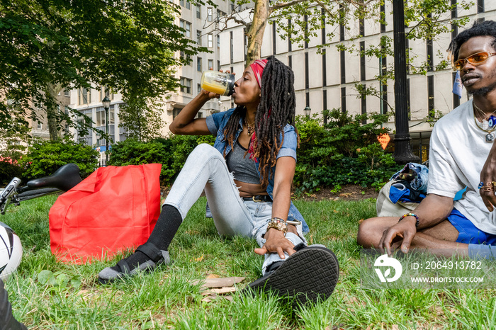 USA, Stylish young friends sitting on grass in park