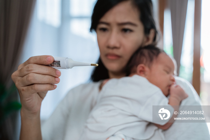 asian mother using thermometer feel worried about their childrens health in the house