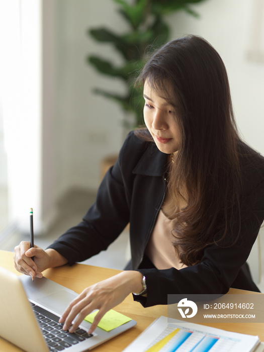 女性在办公室里用笔记本电脑和商务文书工作的裁剪镜头