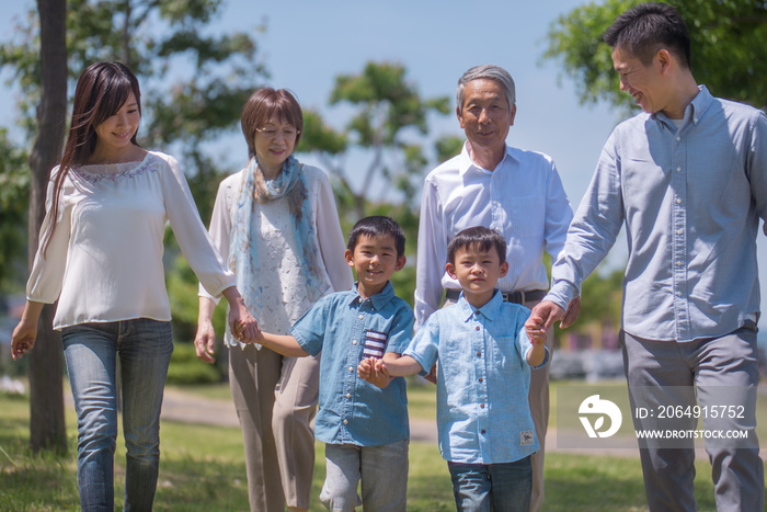 手を繋いで公園を歩く三世代家族