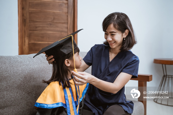 Kindergarten graduation. Asian mother and kid preparing on her kinder graduate day at home