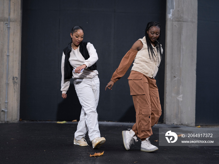 Two teenage girls dancing in city