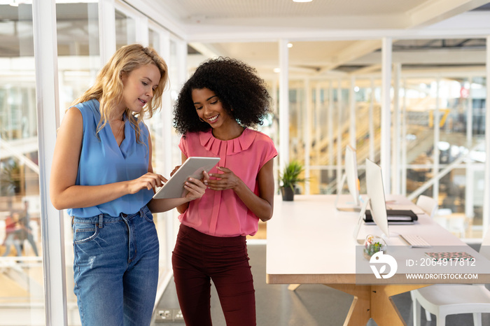 Female executives discussing over digital tablet in office