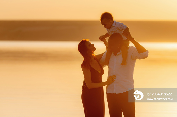 Portrait of happy multiracial family with little biracial son. Beautiful sunset on the beach