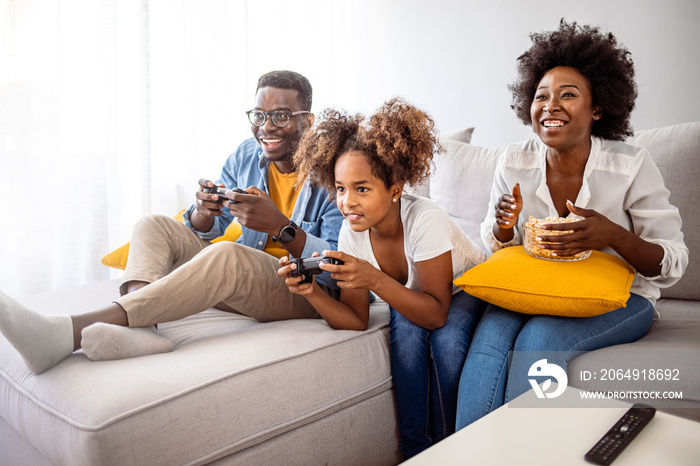 微笑的一家人一起坐在沙发上玩电子游戏。微笑的一家坐在沙发里