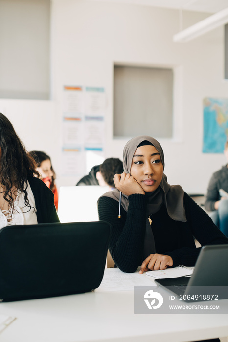 Bored female student studying in classroom at university