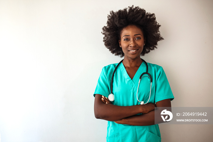 Portrait of a nurse standing in a hospital. Female nurse looking towards camera, wearing blue scrubs