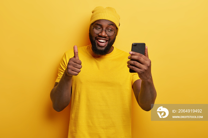 I like your idea. Black smiling guy makes video call via cell phone, keeps thumb raised, agrees with