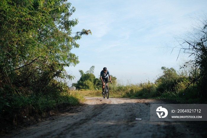 A young bearded cyclist is biking through a dirt path.