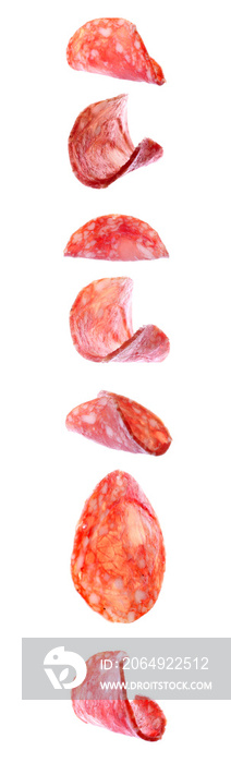 Flying slices of tasty salami on white background