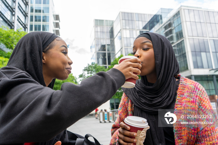 Young women wearing�hijabs�sharing coffee in city