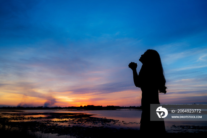 Silhouette of woman pray at sunset