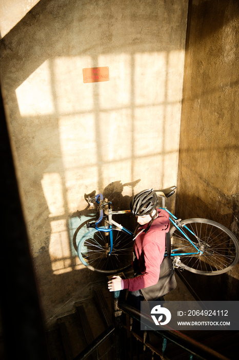 Man in corridor with bike on shoulder