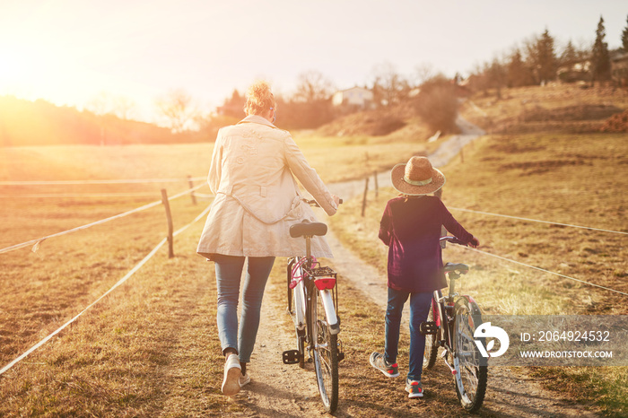 Mother and daughter with bicycles on countryside.