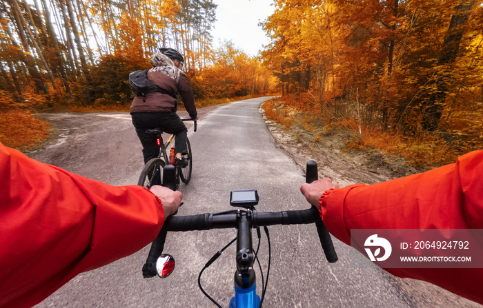 Cyclists on bicycles ride along the road in the autumn forest. POV. Autumn cycling in the forest.