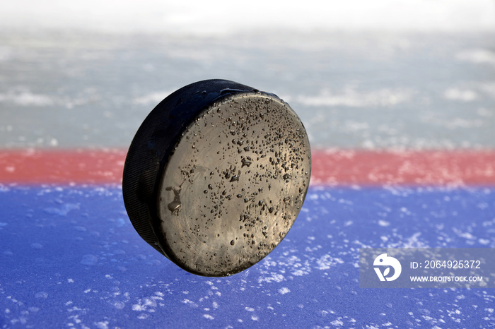 Hockey puck lying on a ice rink.