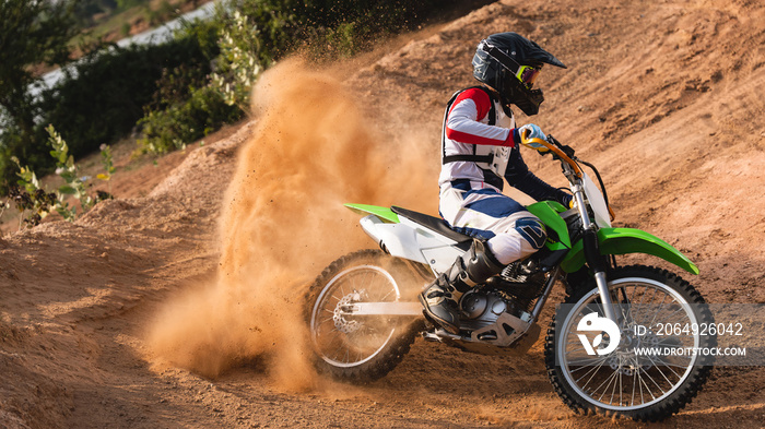 Young man practice riding dirt bike.Splashing sand