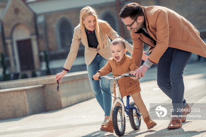 Mom and dad teaching they son to ride a bike