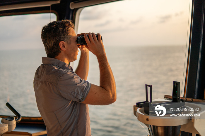 Navigational officer lookout on navigation watch looking through binoculars. Marine industry. COLREG