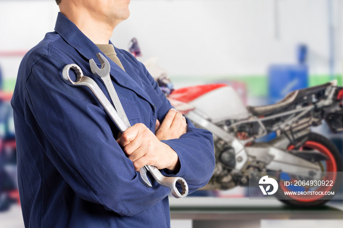 Close up of motorcycle mechanic standing with workshop background with copy space