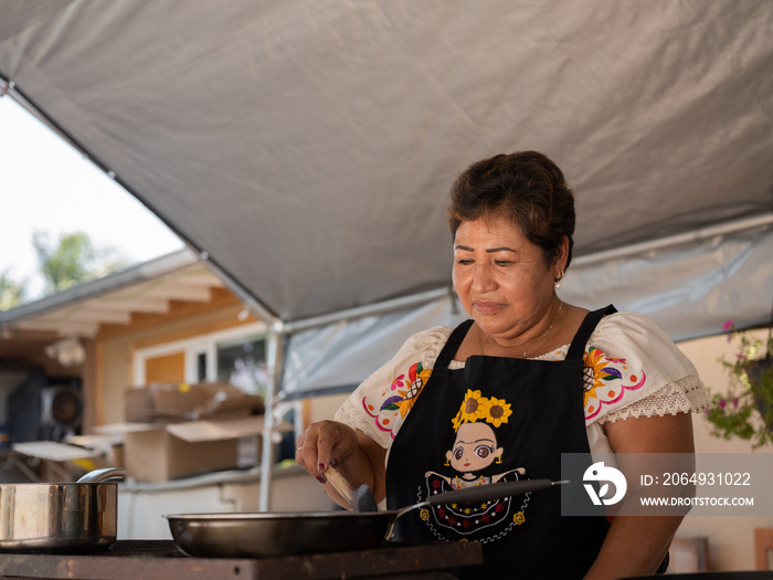 一位土著妇女在炉灶上准备土著食物的水平向上画面