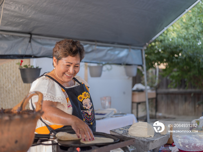 Indigenous woman smiling while making tortillas