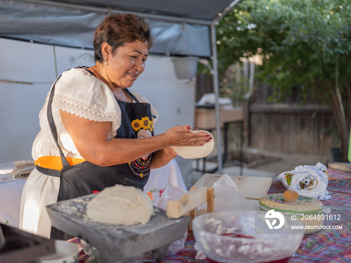 Indigenous woman pressing masa by hand to make tortillas