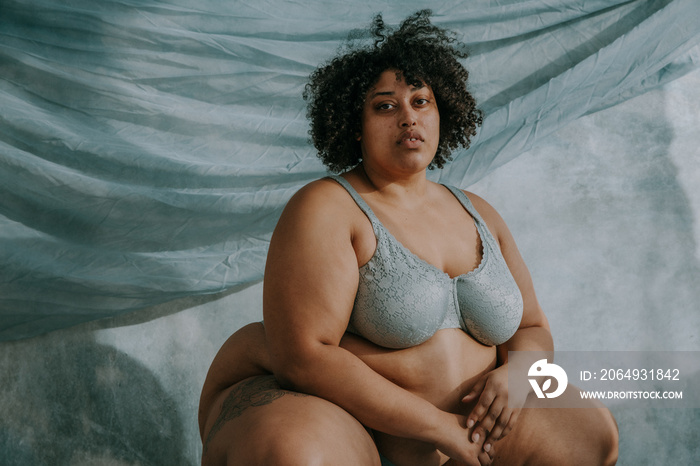 portrait of a plus size afro indigenous person crouching down looking