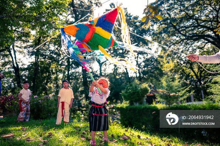 La niña rompiendo la piñata por su cumpleaños en un parque.