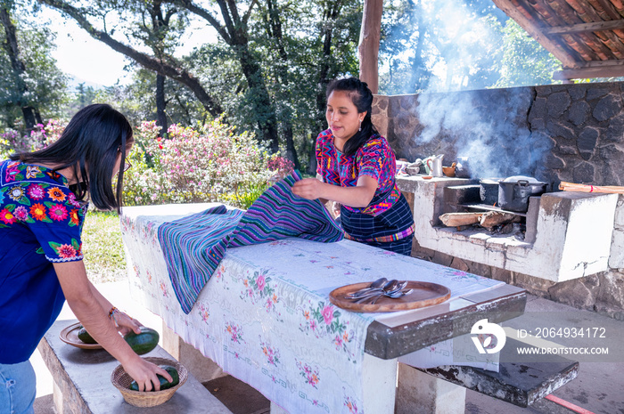 Madre e hija poniendo la mesa para comer。土著家庭。