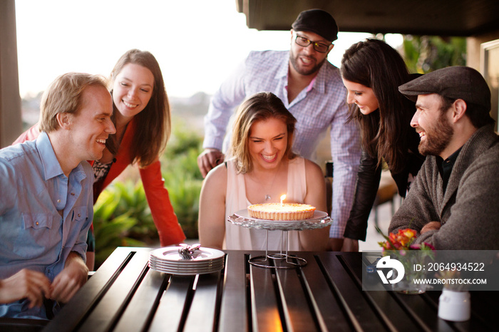 People celebrating friends birthday birthday cake on table outdoors