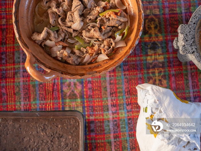 传统粘土锅的俯视图，里面有肉、洋葱和西红柿
