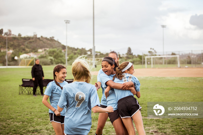 Cheerful female soccer players celebrating on sports field during match