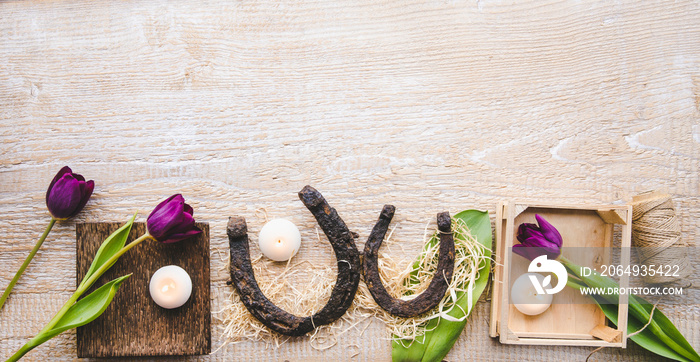 Flat lay view of two rusty small and big horseshoes on light wooden board background, decorated with