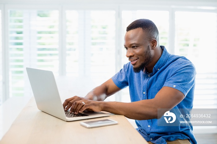 Man sitting at desk and using laptop in living room