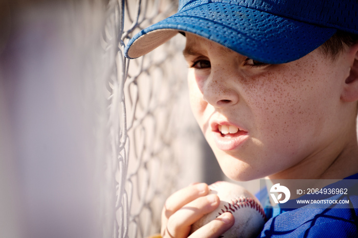 Little league player (8-9) watching game from dugout