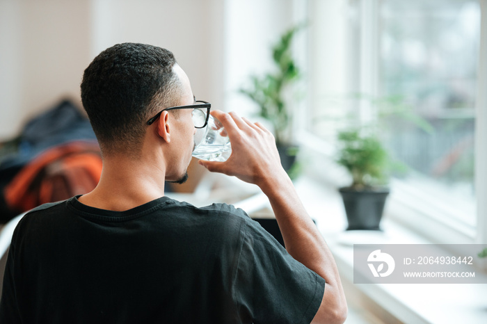 Back view of a young african man drinking water