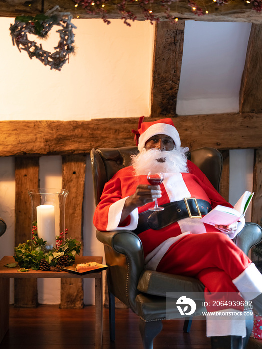 圣诞老人在扶手椅上看书喝酒的肖像？