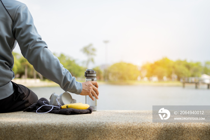 早上跑步后，疲惫的男子坐着拿着水瓶。