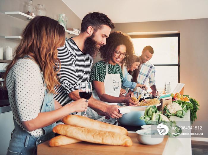 Large group of six friends cooking at table