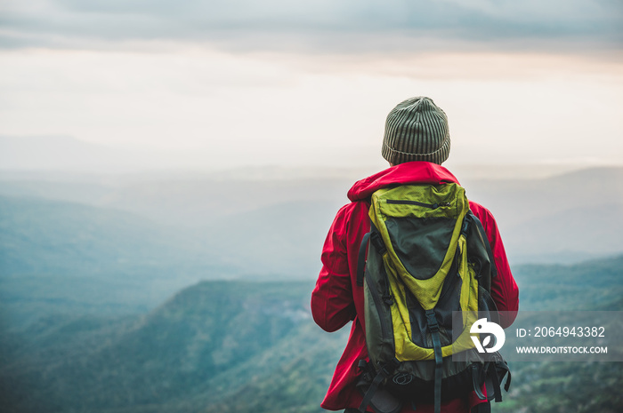 Hikers climbing a red rain jacket carrying a backpack Standing on the edge of a cliff See the beauty