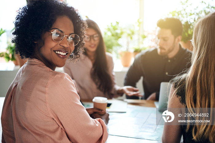 Smiling African businesswoman sitting with diverse coworkers in a boardroom